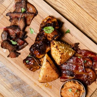 Charcuterie board with bacon, cornbread, and glazed bites