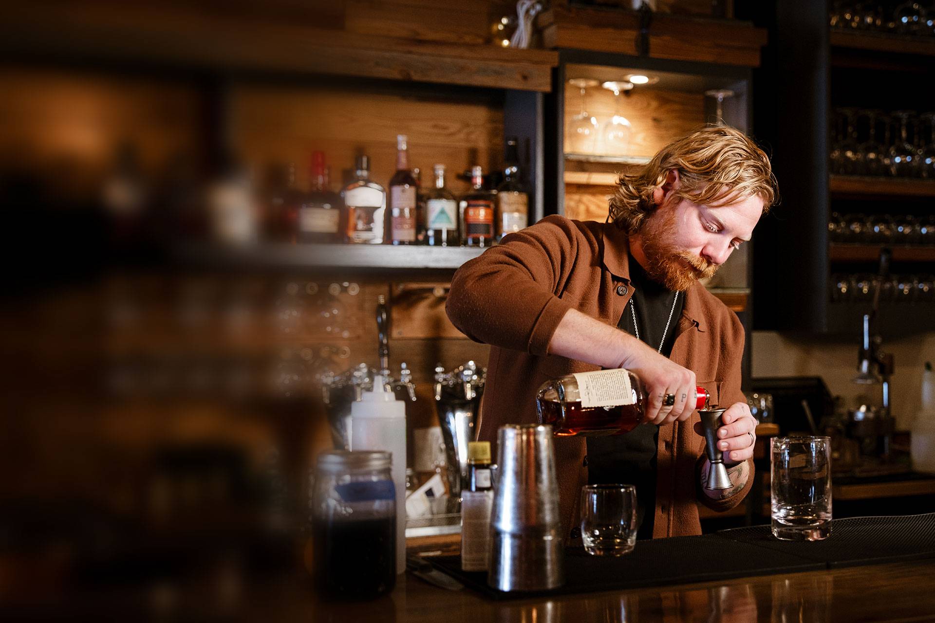 Bartender pouring a whiskey pour behind the bar