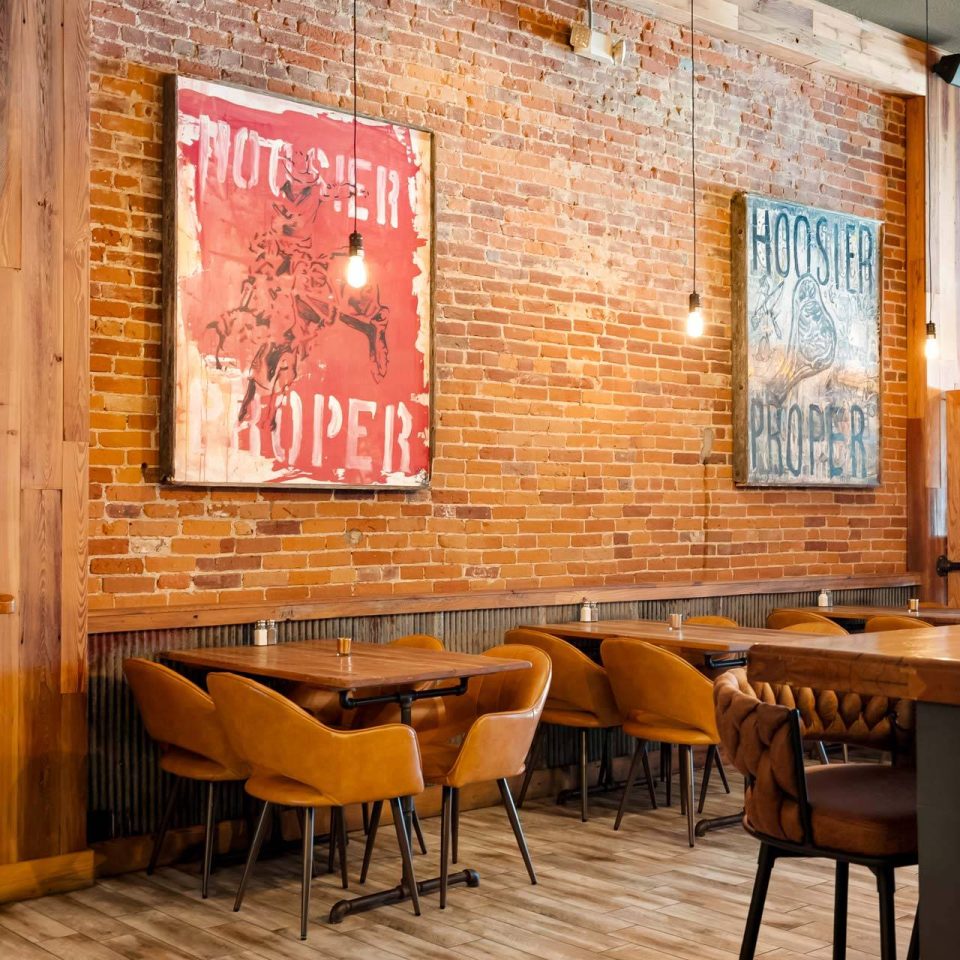 Dining room with Hoosier Proper prints on brick wall