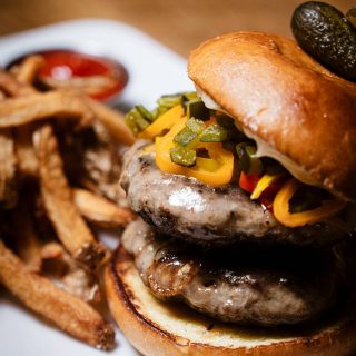 Double smash burger with pickles and peppers, fries on the side