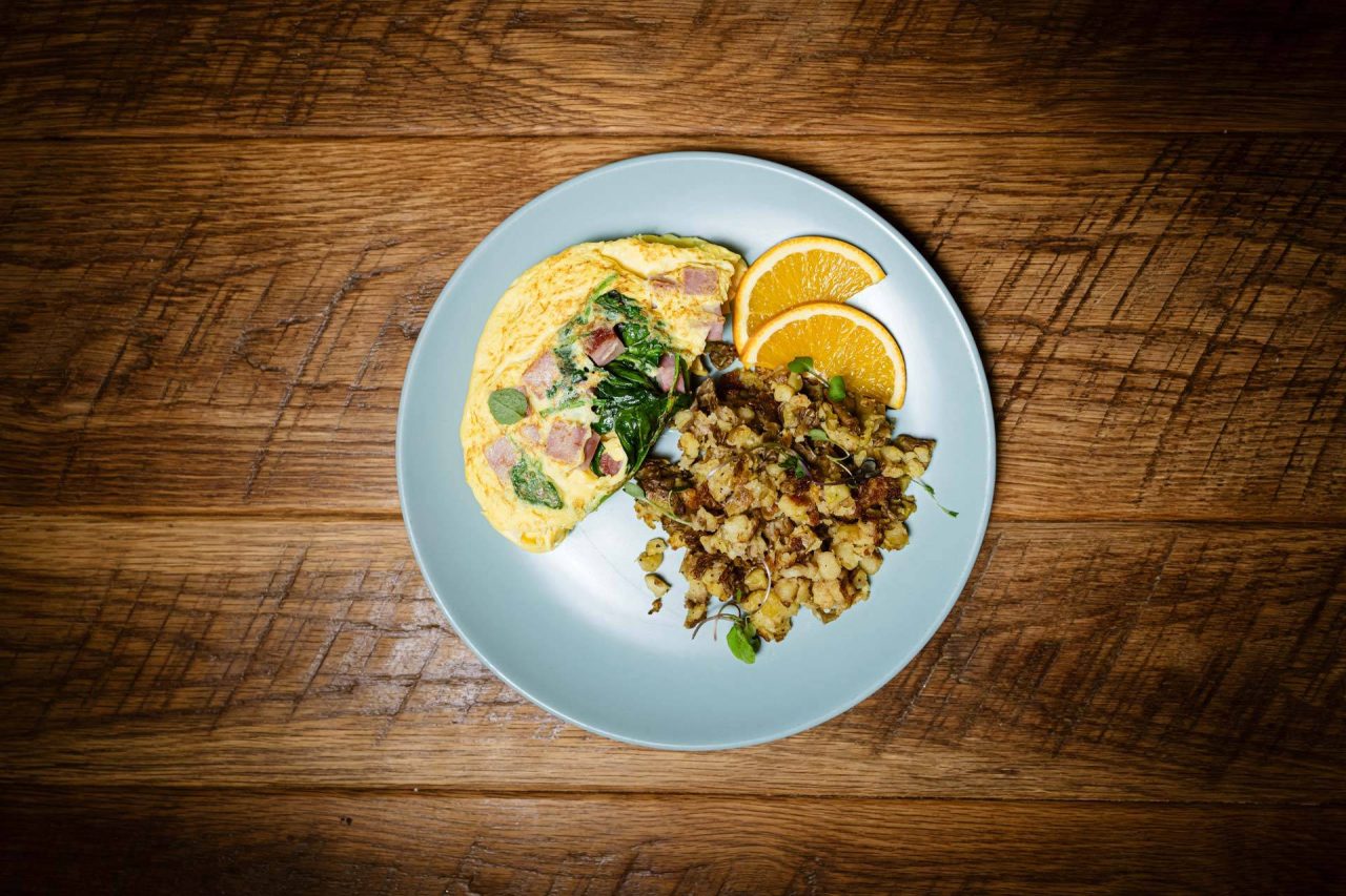 Ham and spinach omelet with breakfast potatoes and orange slices